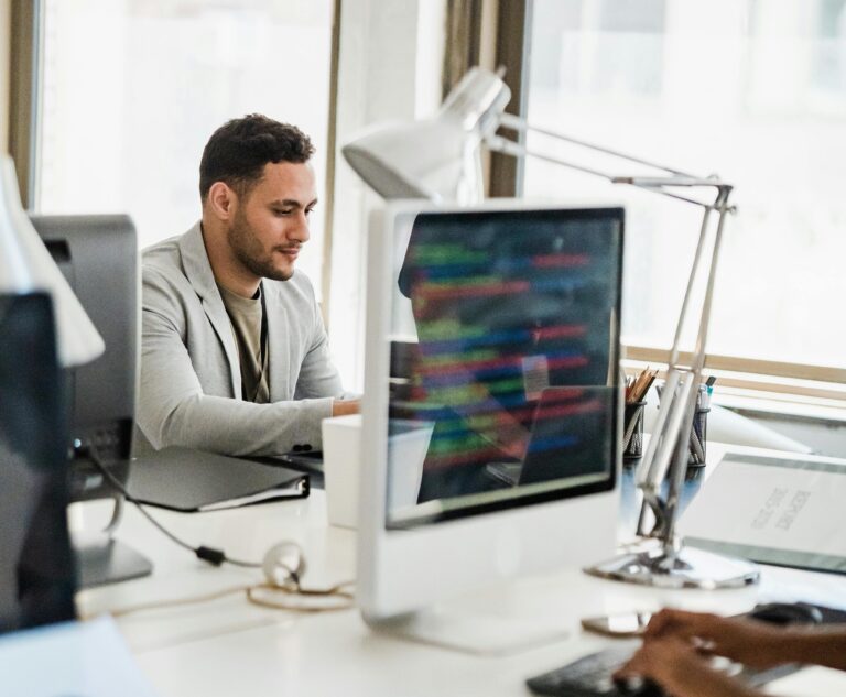 Man wearing a blazer using a hot desk in an office