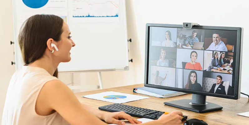 Woman sitting at a desk with a group video call on her computer screen.