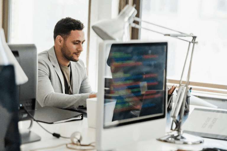 Man wearing a blazer using a hot desk in an office